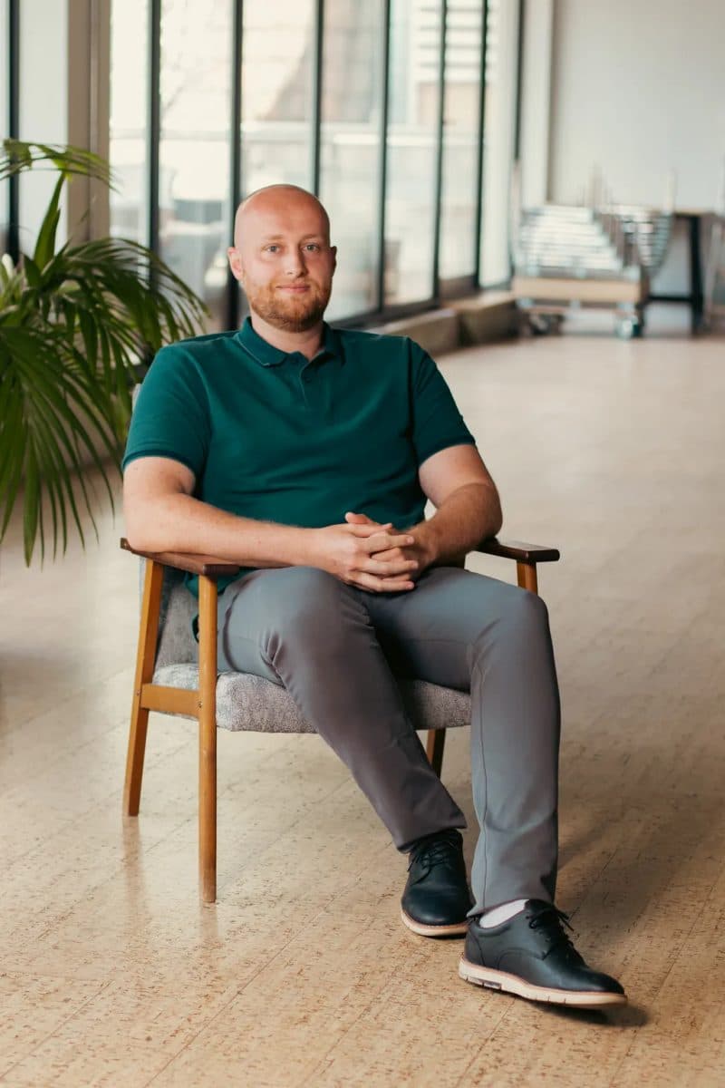 Adam Mould sitting in a wooden armchair